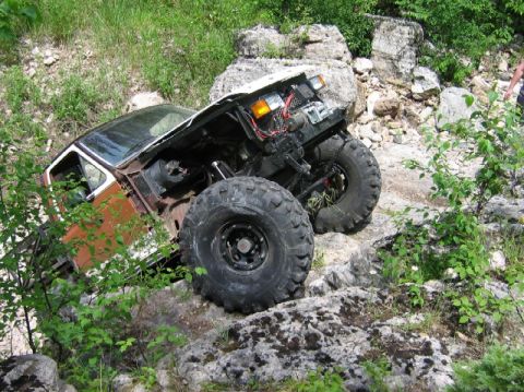 1981 Ford Bronco - This heavily modified off-road vehicle is navigating a rocky terrain with its hood open.