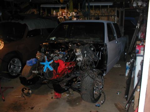 1998 Ford Taurus - A truck sits in a garage with its engine compartment open and parts removed.