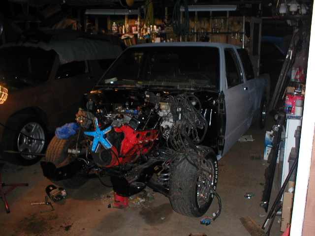 Truck with engine removed, front end disassembled, in a garage