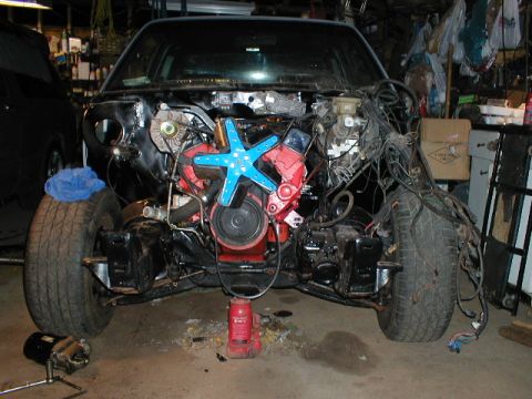 1998 Ford Taurus - The front end of a car is shown with its engine exposed, a bright blue fan and a red engine block.