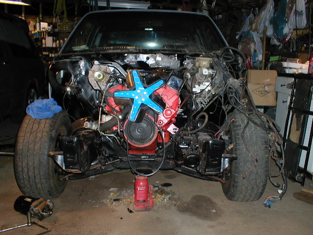 Front view of car with engine exposed, blue fan, red engine block