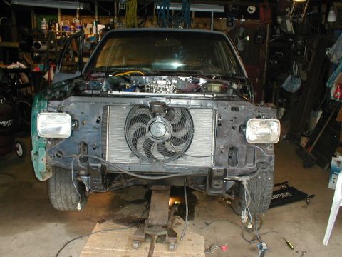 1998 Ford Taurus - The front of a vehicle is shown with its bumper and grille removed, revealing the radiator and fan assembly.