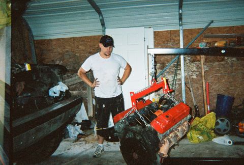 1988 Ford Bronco - An engine is suspended by a hoist in a garage, with a person standing nearby.