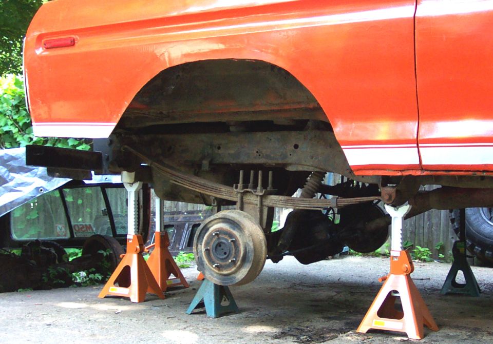 1978 Ford Bronco rear axle and suspension on jack stands, orange body