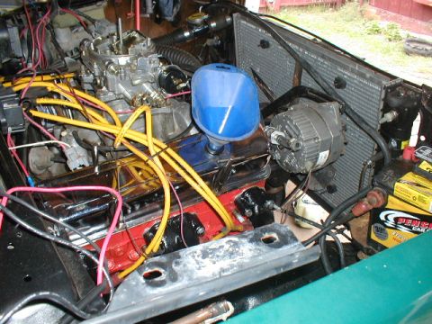 1998 Ford Taurus - Close-up view of an engine bay, a carburetor, alternator, and various wires. A blue funnel is visible, suggesting recent maintenance.