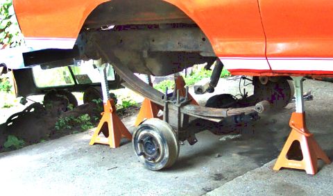 1978 Ford Bronco - Rear axle assembly of an orange vehicle is disassembled and supported by jack stands.