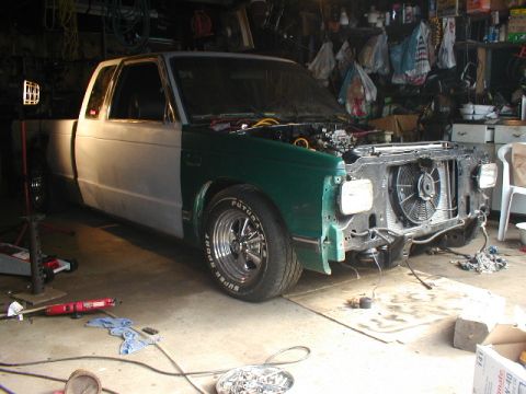 1998 Ford Taurus - This pickup truck is undergoing repairs in a cluttered garage, with its front end disassembled.