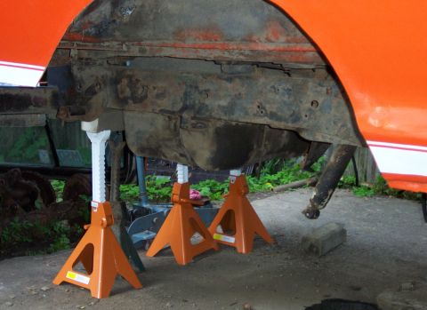 1978 Ford Bronco - Vehicle's undercarriage supported by jack stands, revealing frame and fuel tank components.