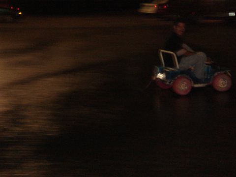 1996 Ford Probe - A person drives a small blue toy car with red wheels at night.