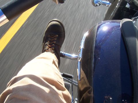 1994 Ford F-150 - A rider's view from a motorcycle, with a boot in frame and the blue bodywork reflecting the sun.