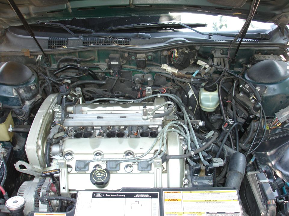1995 Ford Taurus engine bay with V6 engine, alternator, and fluid reservoirs visible