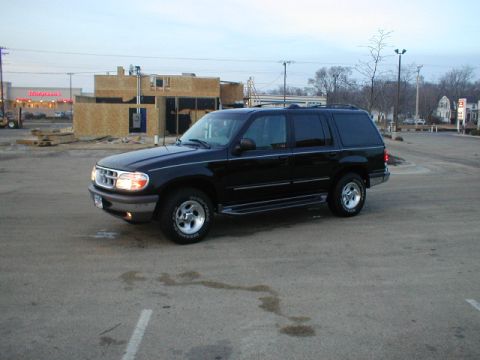 1998 Ford Taurus - A black SUV is parked in a lot with a construction site behind it.