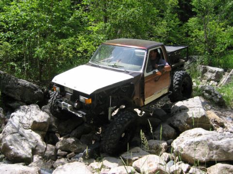 1981 Ford Bronco - This modified truck navigates a challenging rocky path through a wooded area.