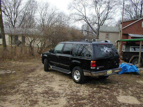1998 Ford Taurus - This black SUV, possibly a 1998 model based on visible badging, is parked outdoors in a rural setting.