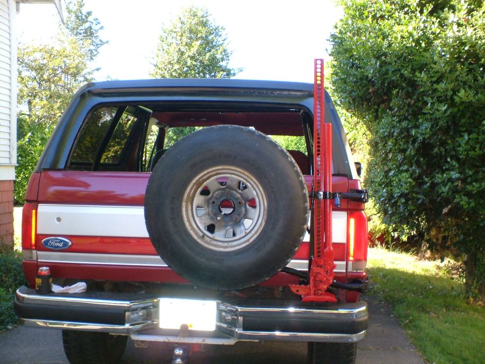 Red SUV rear view with spare tire and Hi-Lift jack