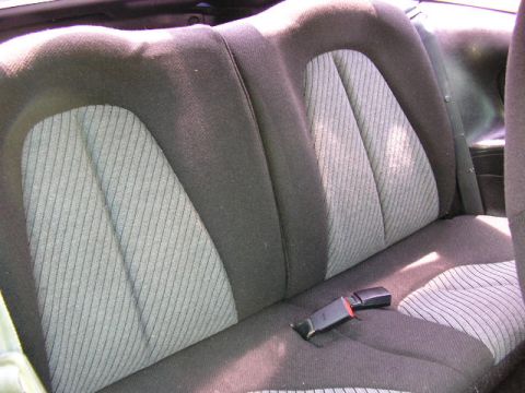 1994 Ford Probe - The interior of a vehicle shows the rear seat with distinctive fabric patterns and a seatbelt.