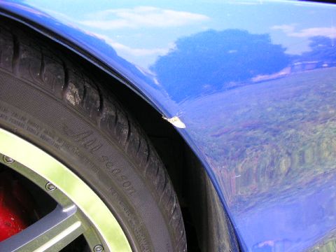 1994 Ford Probe - A close-up view of a blue car's fender and tire, showing a minor paint chip.