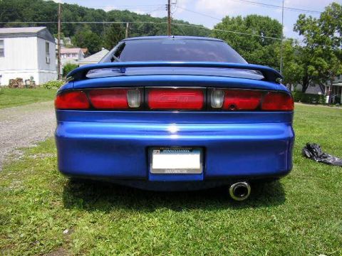 1994 Ford Probe - The rear of a blue 1994 Ford Probe GT is parked on a grassy lawn with houses in the background.