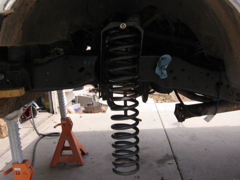 1990 Ford Bronco - Vehicle suspension work in progress, showing a detached coil spring and chassis components.