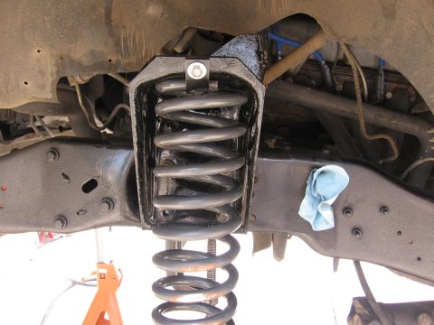 1990 Ford Bronco - Close-up view of a front suspension coil spring assembly, likely undergoing maintenance or modification.