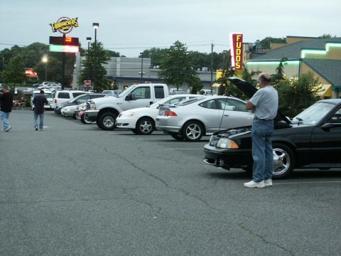 2001 Mercury Grand Marquis - A parking lot gathering features several vehicles under an overcast sky.