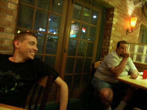 2001 Mercury Grand Marquis - Two men are seated at tables inside a restaurant, one smiling and the other gesturing.