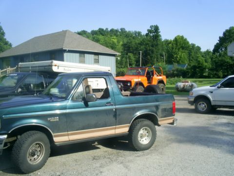 1994 Ford Bronco - Three vehicles are parked in a driveway in front of a house on a sunny day.