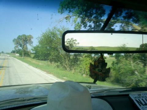 1994 Ford Bronco - A view from inside a vehicle driving on a sunny day through a rural landscape, with a cowboy hat on the dashboard.