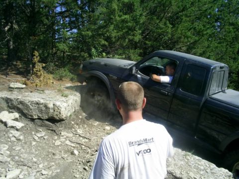 1994 Ford Bronco - A black pickup truck maneuvers over rocks on an off-road trail.