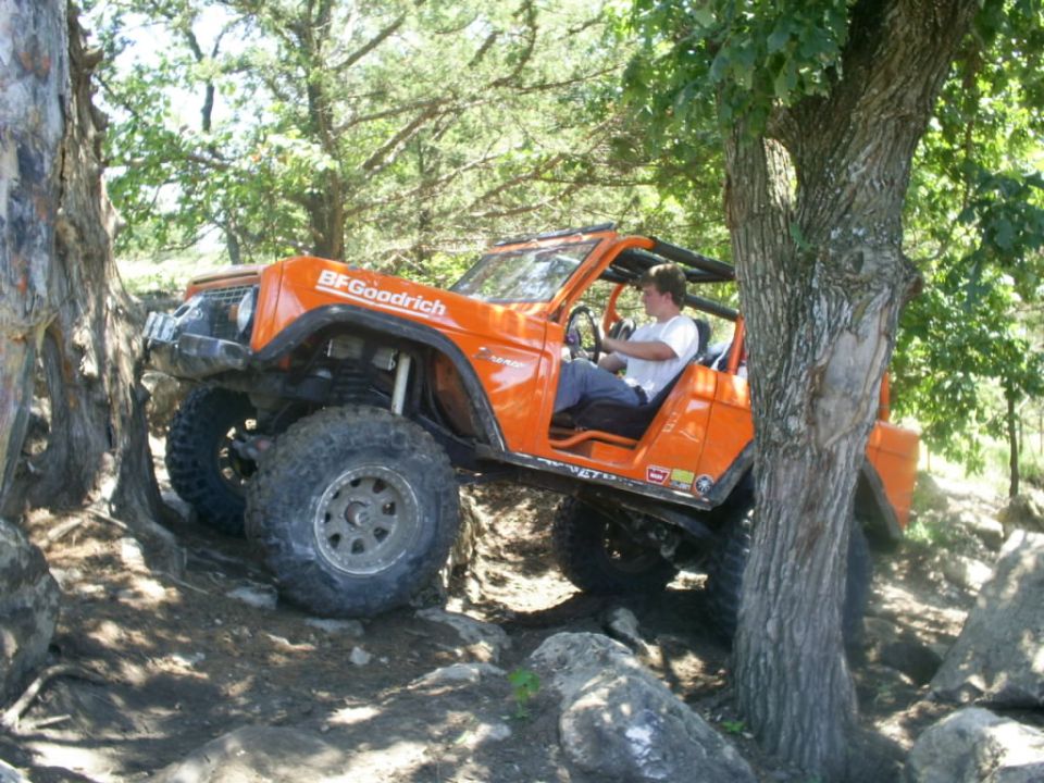 Orange 1994 Ford Bronco off-roading over rocks