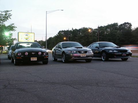 2001 Mercury Grand Marquis - Three Ford Mustangs are parked in a lot at dusk.