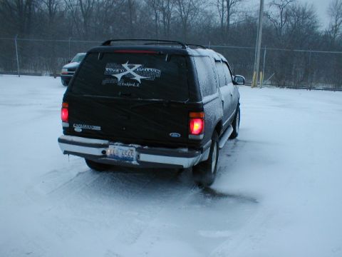 1998 Ford Taurus - A black SUV is parked in a snowy lot, with another vehicle visible in the background.