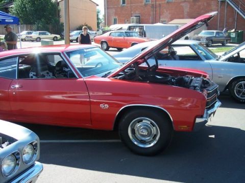 1972 Ford Ranchero - A red muscle car with its hood open is displayed at an outdoor event, with other vehicles nearby.