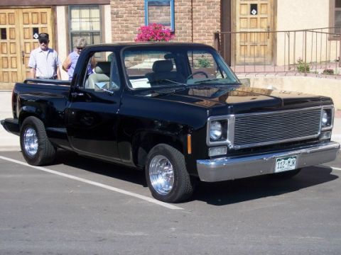1972 Ford Ranchero - This black pickup truck, likely a 1973 model, is parked in front of a building.