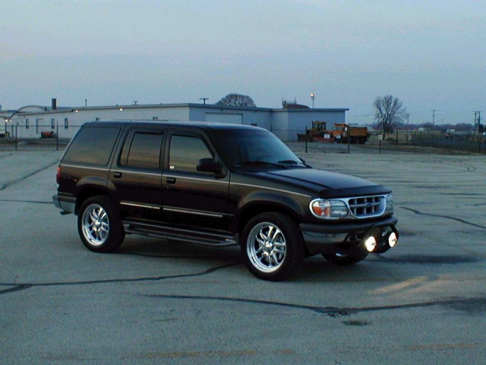 Black SUV with chrome wheels and aftermarket fog lights, parked on asphalt