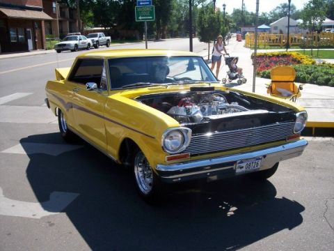 1972 Ford Ranchero - A yellow 1964 Chevrolet Nova SS is parked with its hood open, revealing the engine bay.