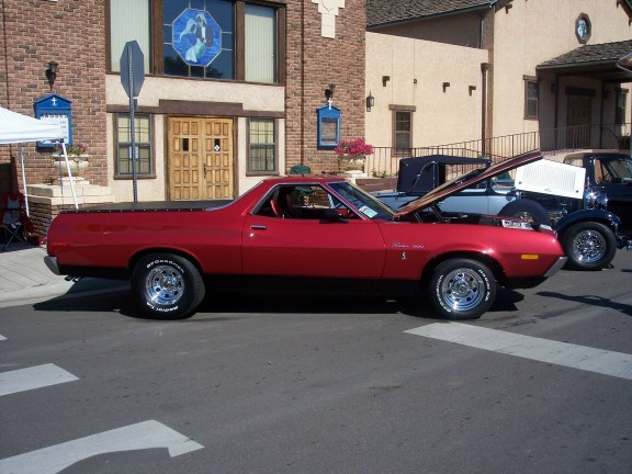 Red 1972 Ford Ranchero parked on street, hood open, with other vehicles behind