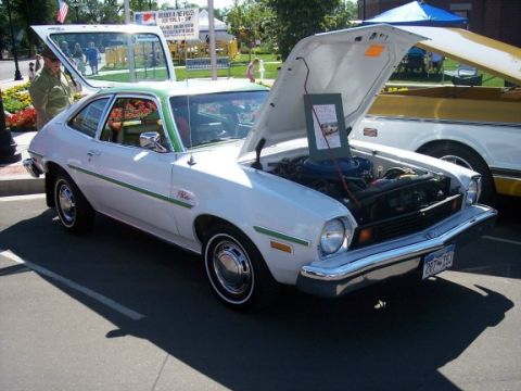 1972 Ford Ranchero - White Ford Pinto sedan with green trim and hood open at an outdoor car show.