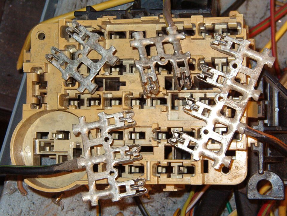 Rear of a fuse panel with several metal contact strips pulled loose from the housing