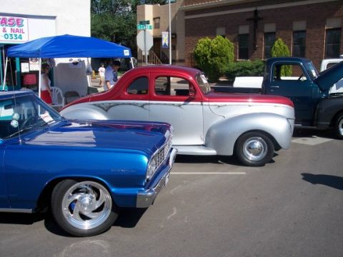 1972 Ford Ranchero - Several vehicles are parked in a lot, including a blue car, a custom coupe, and a pickup truck.