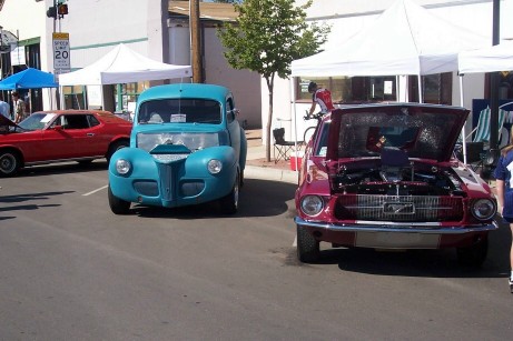 1972 Ford Ranchero - A blue hot rod and a red Mustang are parked on a street, with tents set up in the background.