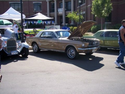 1972 Ford Ranchero - A gold 1965 Ford Mustang coupe is displayed with its hood open at an outdoor car show.