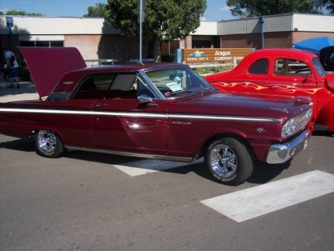 1972 Ford Ranchero - Maroon Ford Falcon with hood and trunk open parked next to a red hot rod at a car show.