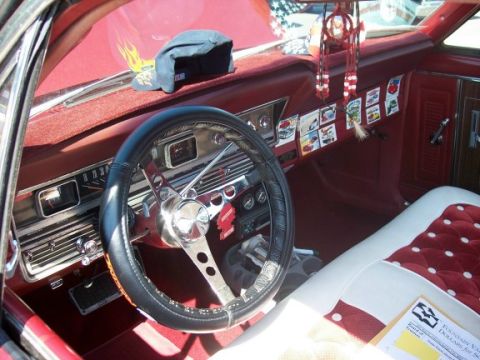 1972 Ford Ranchero - The interior of a 1972 Ford Ranchero features a custom steering wheel, numerous dashboard decals, and a distinctive red and white seat patt…