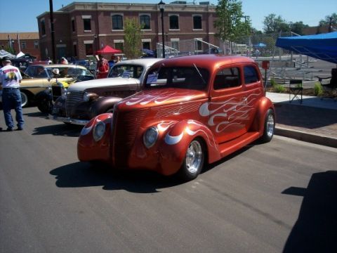 1972 Ford Ranchero - A custom orange sedan with flame decals is parked at an outdoor event.