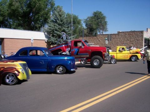 1972 Ford Ranchero - Multiple custom vehicles are parked on a street, including a blue coupe and a yellow pickup truck with flame graphics.