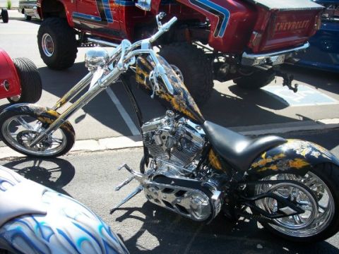 1972 Ford Ranchero - A custom chopper motorcycle is parked next to a lifted red Chevrolet truck.