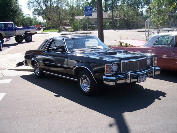 Black 1977 Ford Ranchero with chrome grille and hood scoop, parked on asphalt
