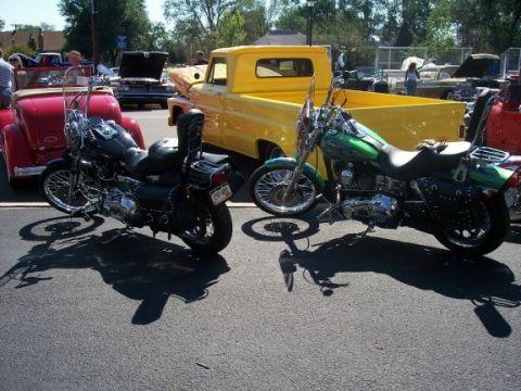 1972 Ford Ranchero - Two custom motorcycles are parked at an outdoor car show, with classic cars visible in the background.