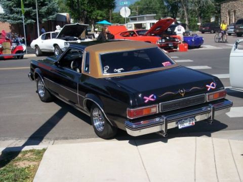 1972 Ford Ranchero - Rear view of a black coupe with a gold vinyl roof, parked on a street with other vehicles present.